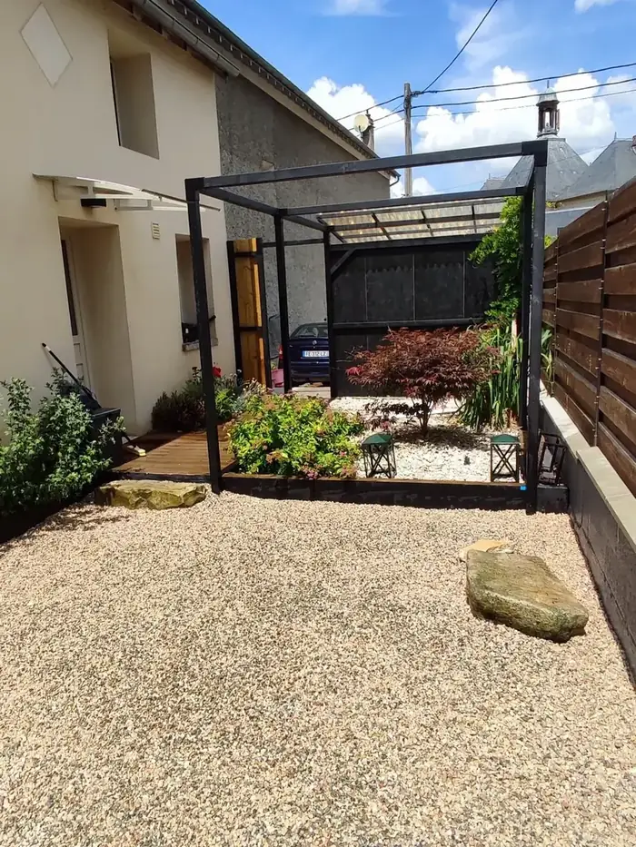 Terrasse abritée par une pergola, cour en gravier stabilisé