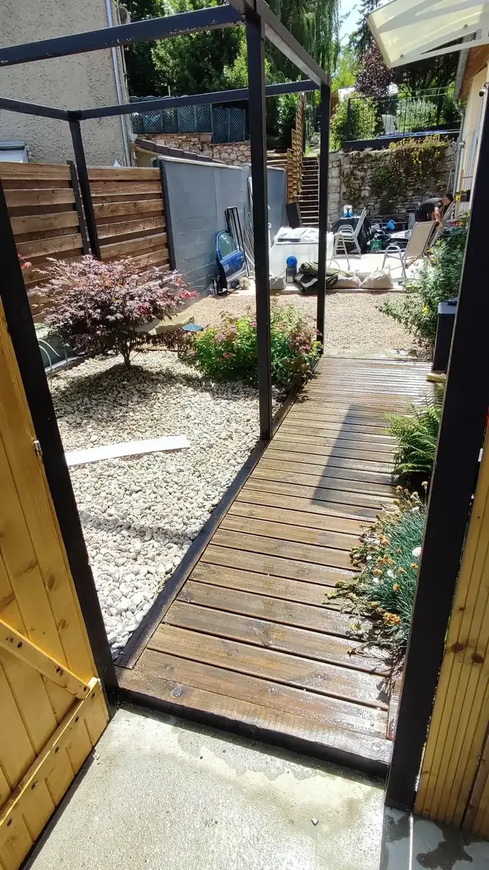 Terrasse en bois et allée sous une pergola vitrée