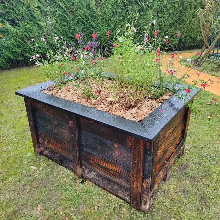 Jardinière en bois brûlé plantée de fleurs